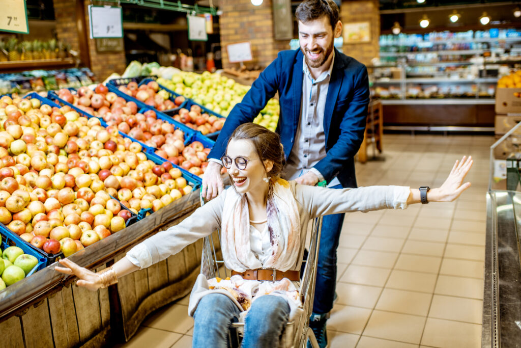 A man pushing a woman on a shopping cart.